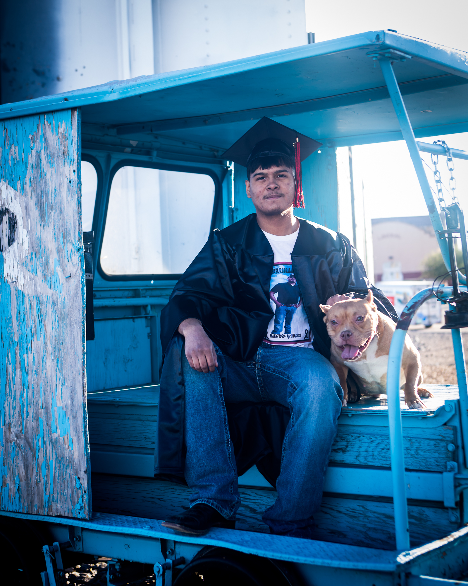 boy sitting in truck with his dog wearing a graduation hat