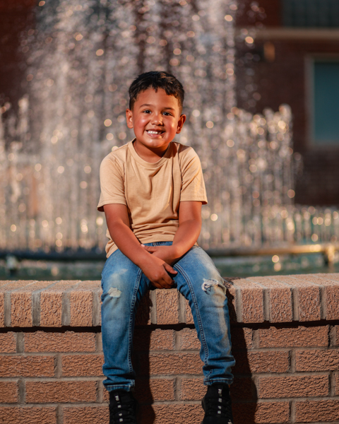boy sitting on a fountain ledge